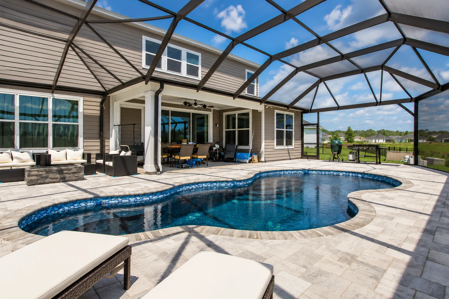 Screened patio enclosure surrounding a swimming pool, with a dark metal frame and views of the house and yard.