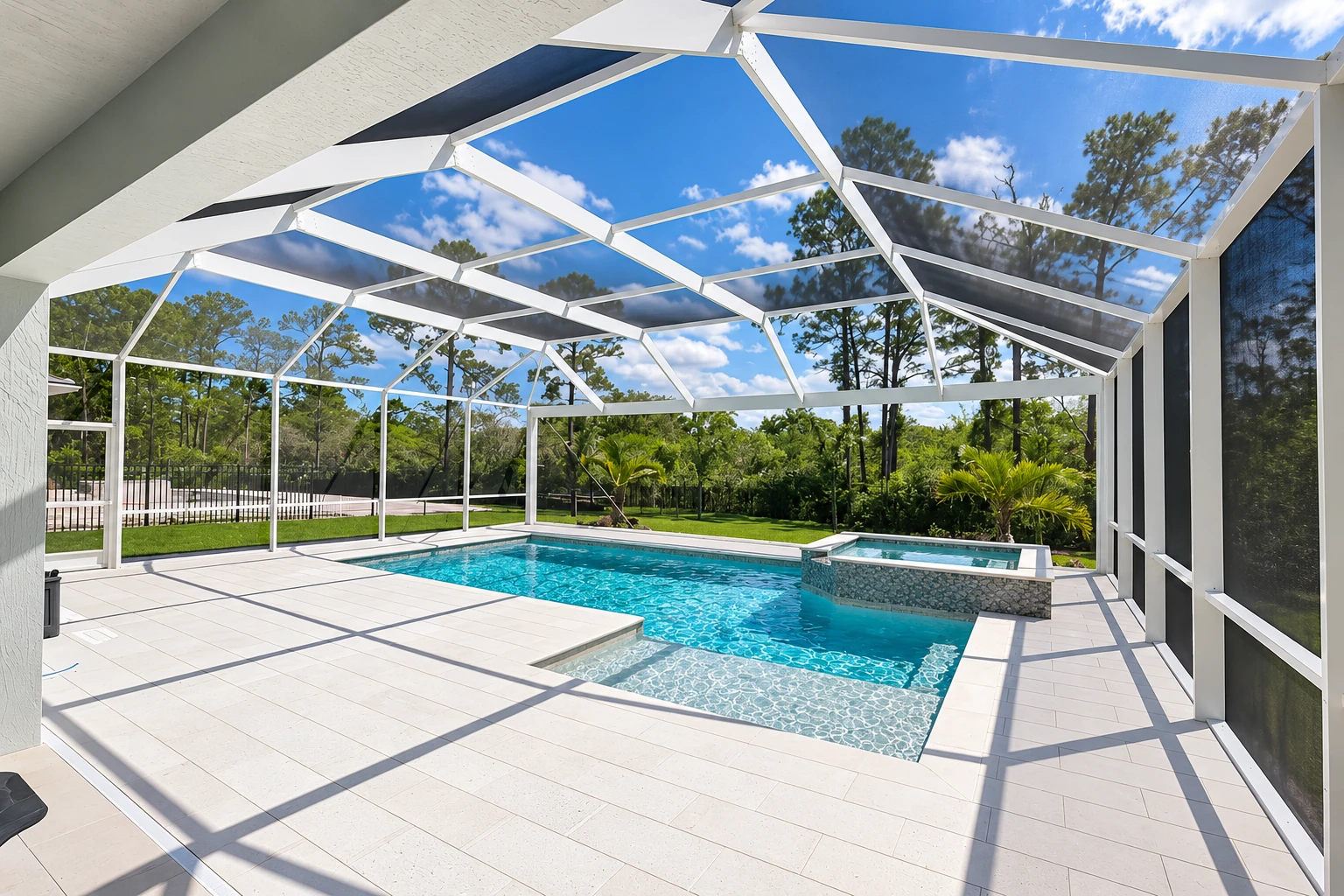 A white-framed patio enclosure surrounds a turquoise swimming pool, with mesh walls and a screened roof beneath a bright blue sky.