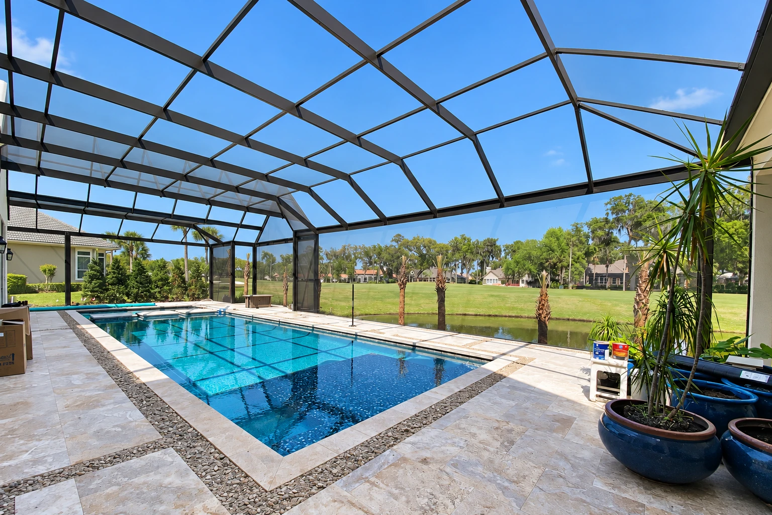 A screened pool enclosure has a dark metal roof frame, tiled deck, and a rectangular swimming pool.